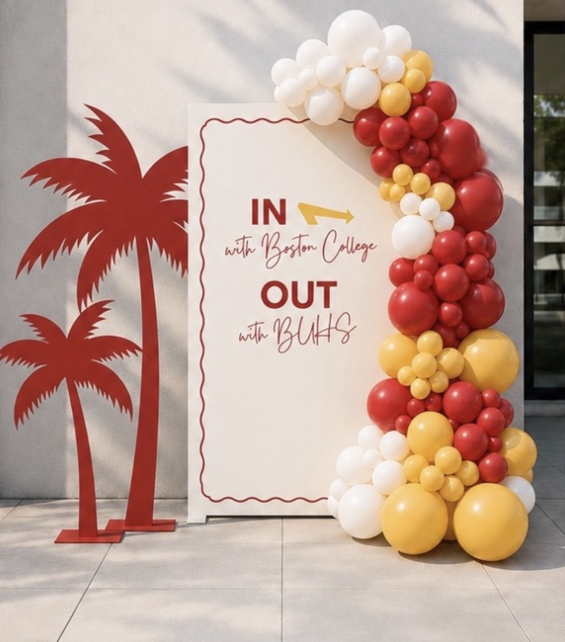 Photorealistic mockup of a maroon, gold and white graduation sign with palm cutouts and organic garland