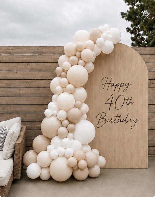 AI mockup — neutral cream and taupe balloon garland on a wood arch backdrop