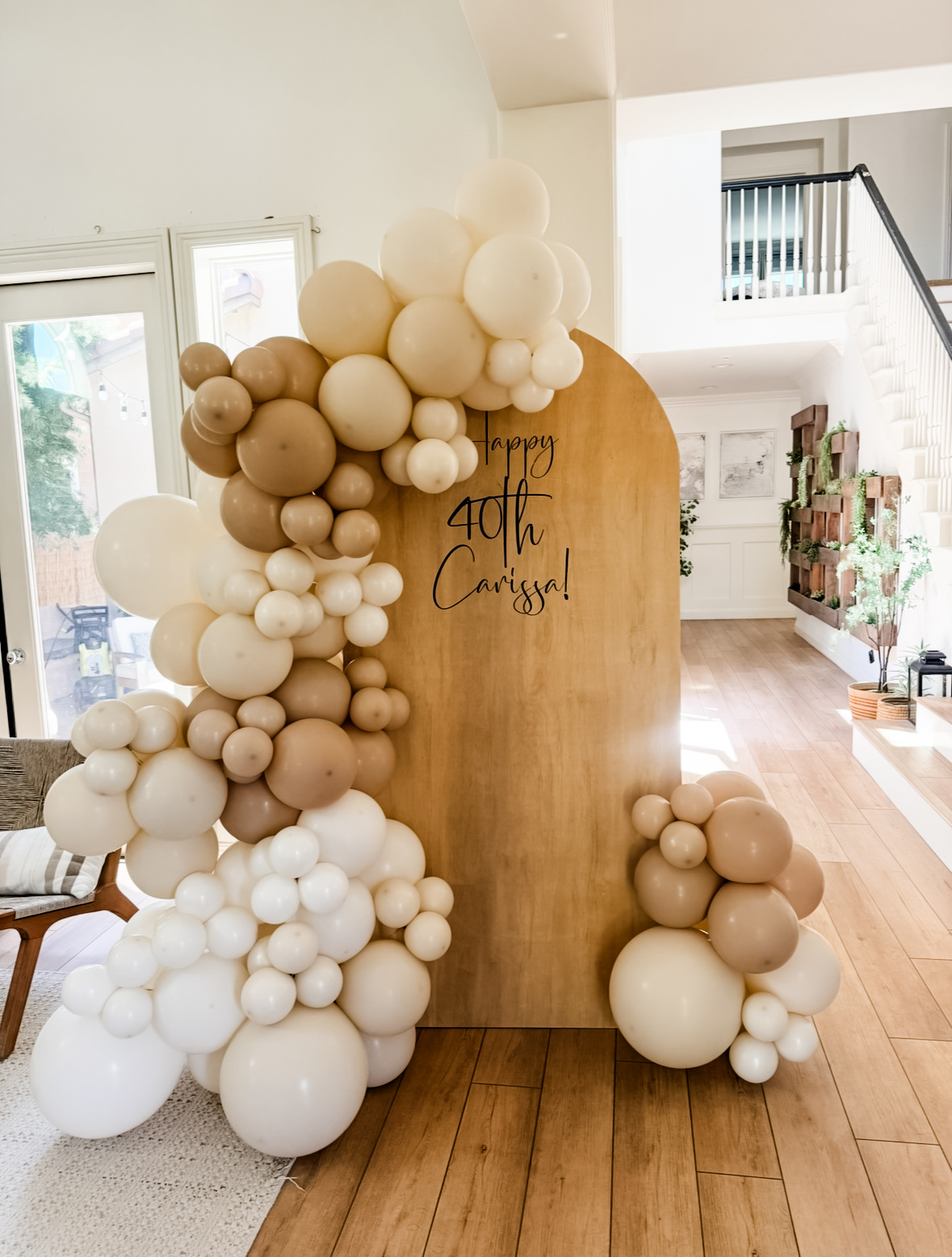 Real install — neutral cream and taupe balloon garland on a wood arch backdrop