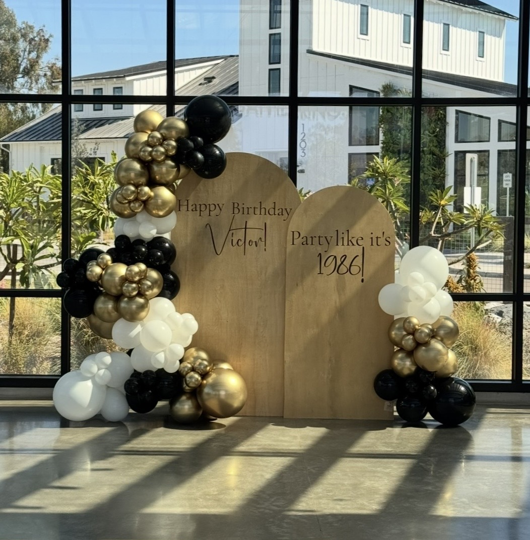 Real install — black, white and gold balloon garland on twin arch backdrops