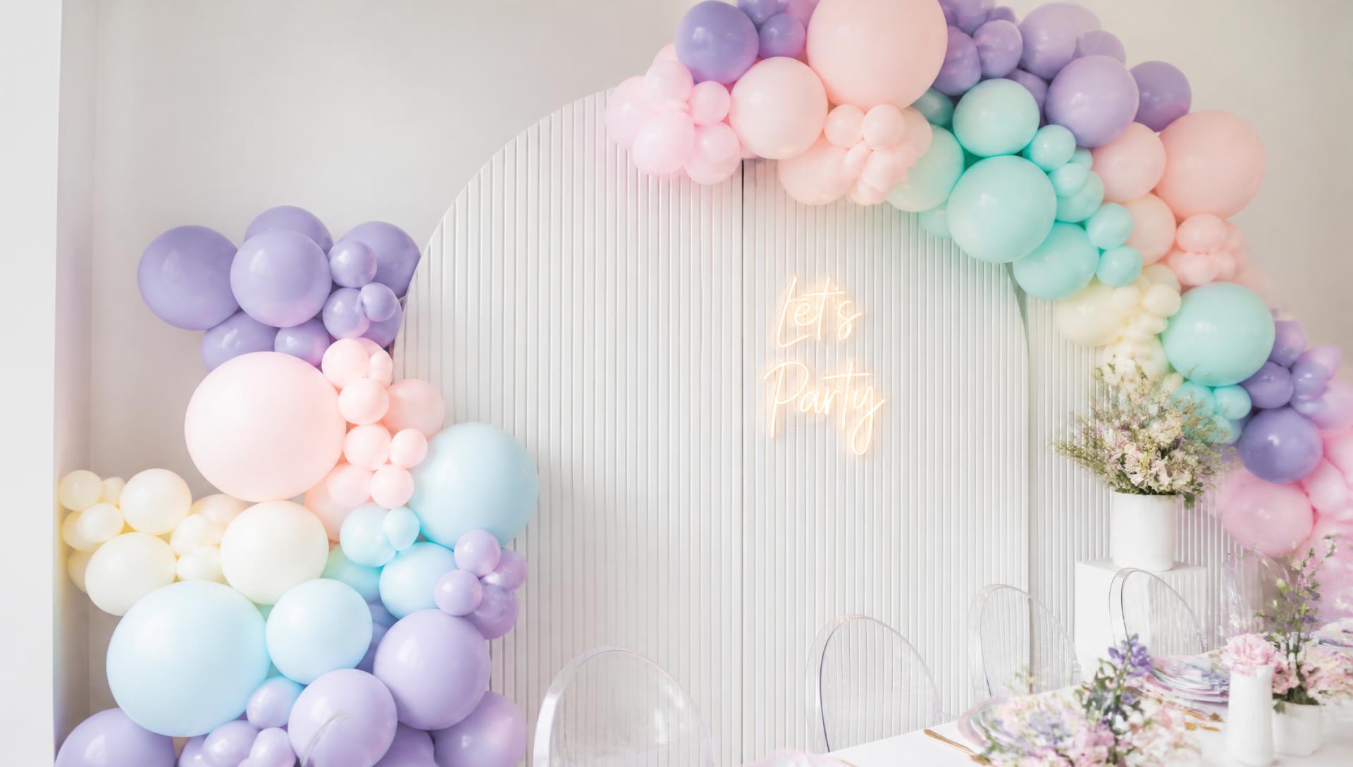 Pastel lavender, blush and aqua balloon installation over a fluted arch backdrop