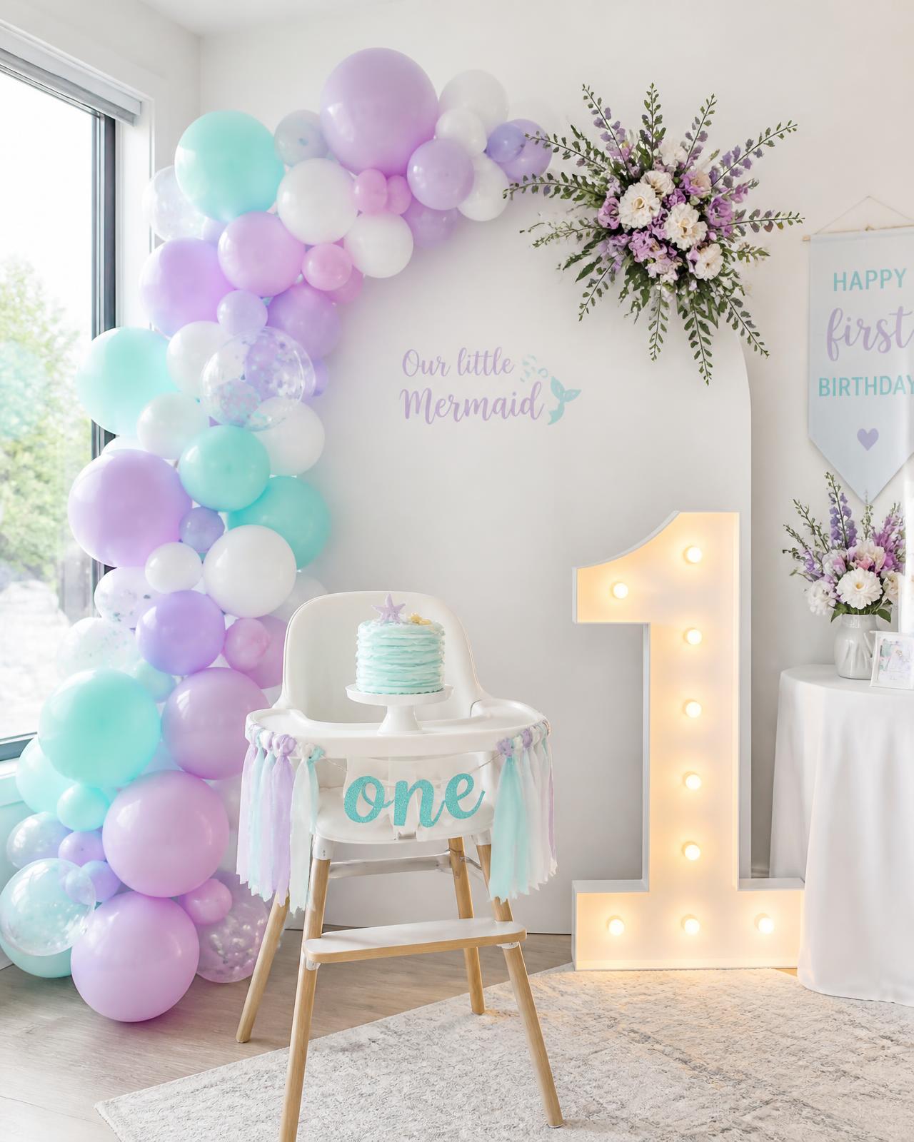 Lavender and aqua balloon garland with a marquee number one at a first birthday
